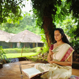 Spiritualistic Hindu woman meditating using rosary or japa mala in the garden.
