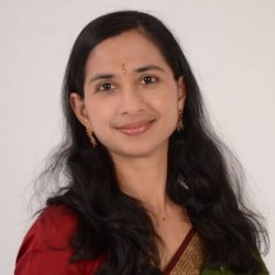 Portrait of Smt. Parvathi Sriram smiling in a red and green saree on a white background